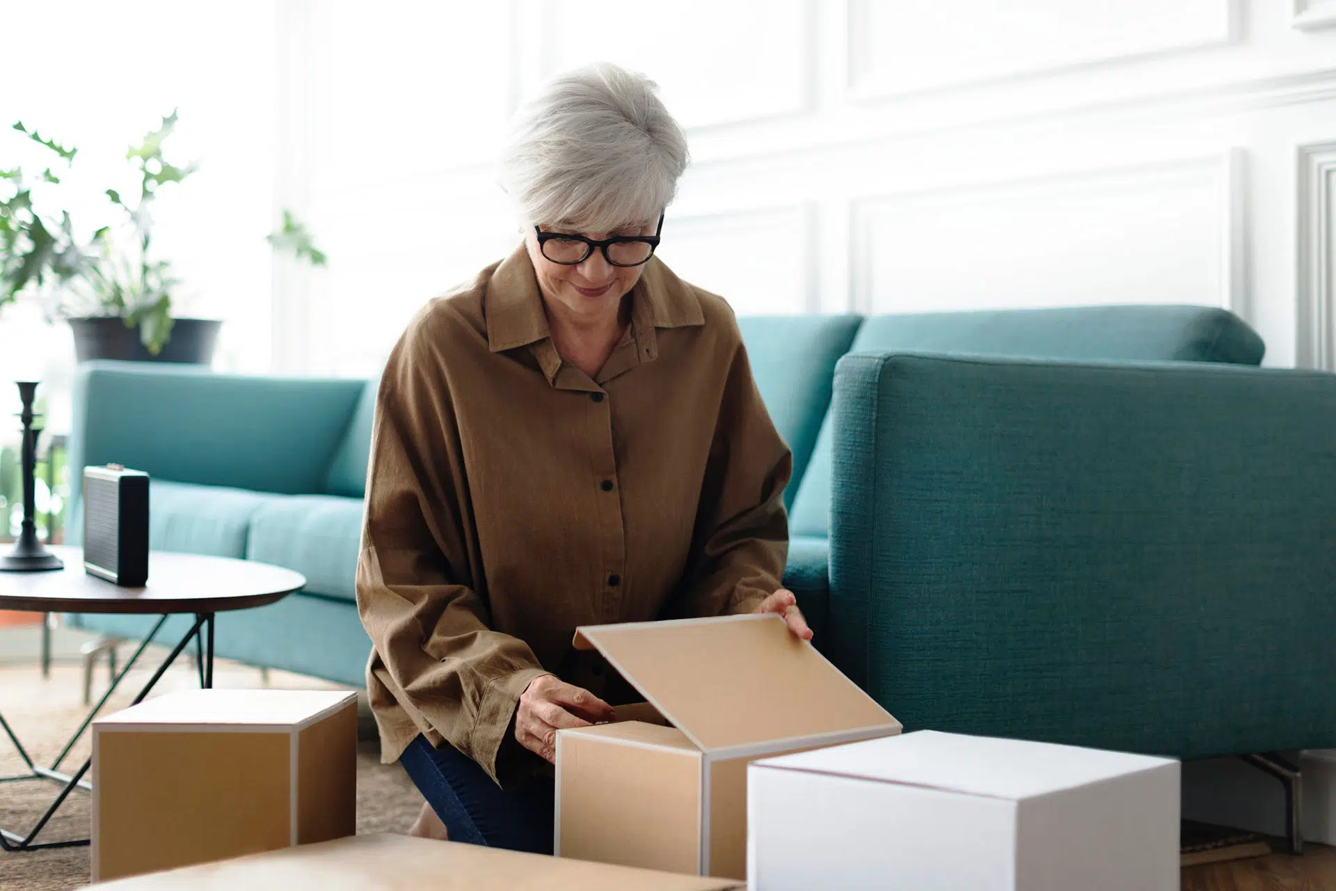 Senior woman packing brown boxes in the living room